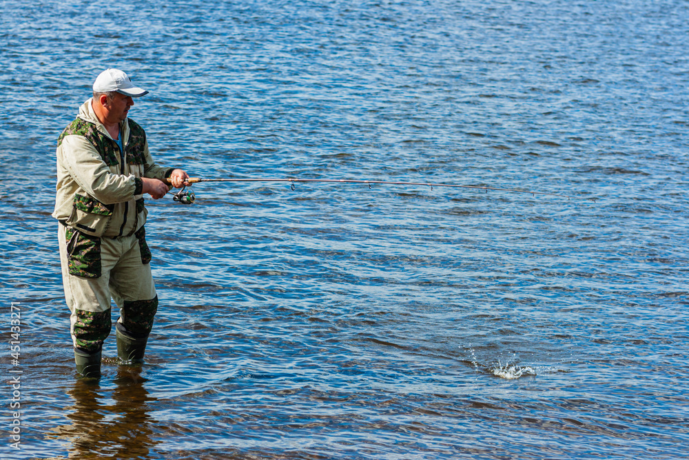 Fishing on the river. Fishing. Spinning. Fisherman spins a reel, catches fish Fishing on the river. Fishing. Spinning. Fisherman spins a reel, catches fish