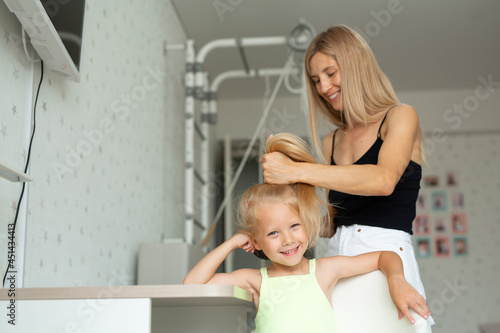 young mom makes her daughter's hair 