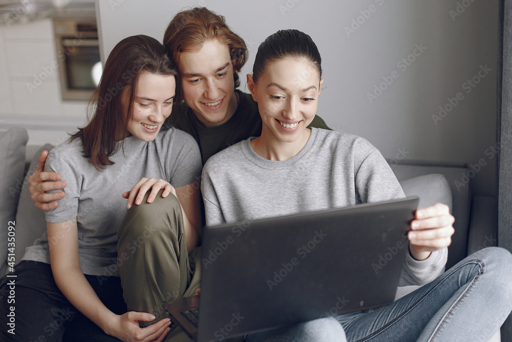 Friends sitting on a bed in a room and use a laptop Friends sitting on a bed in a room and use a laptop