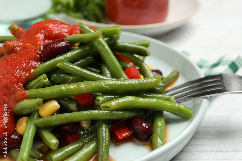 Delicious salad with green beans and tomato sauce served on white wooden table, closeup Delicious salad with green beans and tomato sauce served on white wooden table, closeup