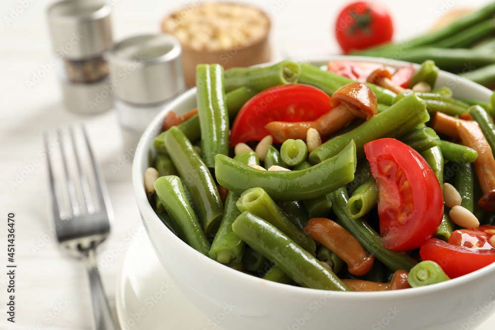 Delicious salad with green beans, mushrooms, pine nuts and tomatoes on white table, closeup Delicious salad with green beans, mushrooms, pine nuts and tomatoes on white table, closeup
