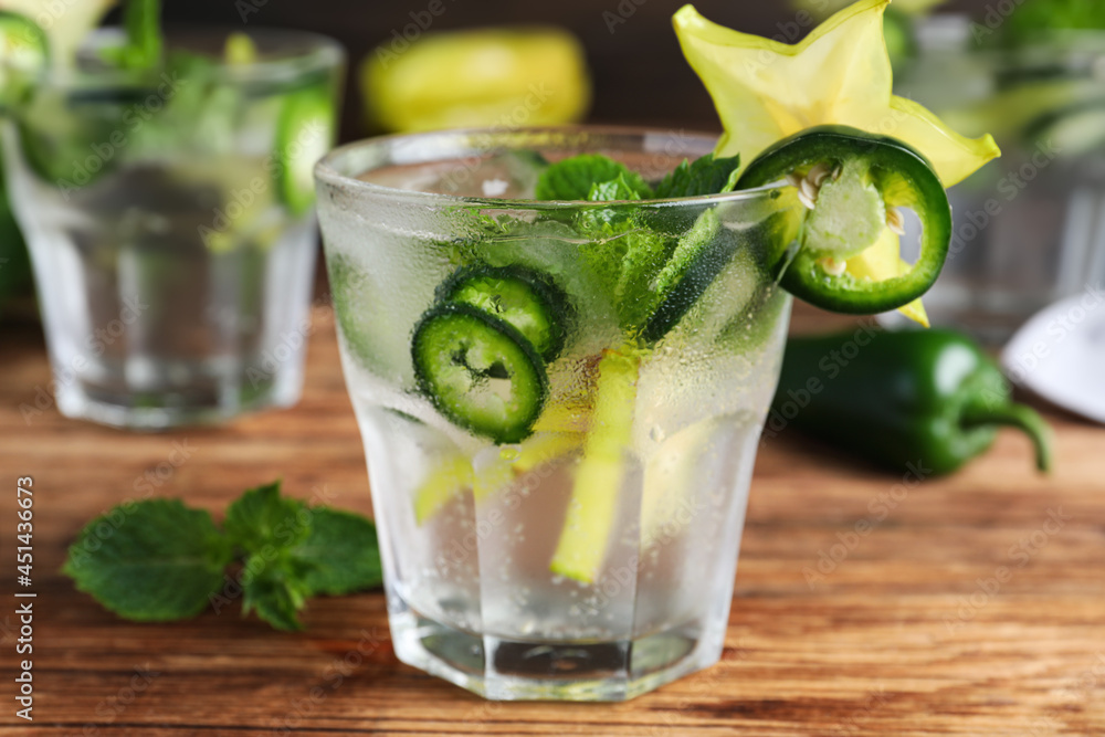 Fototapeta premium Spicy cocktail with jalapeno, carambola and mint on wooden table, closeup