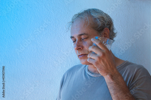 portrait with copy space of mature man with ambient color lights on white background refresh his face with cold drink photo