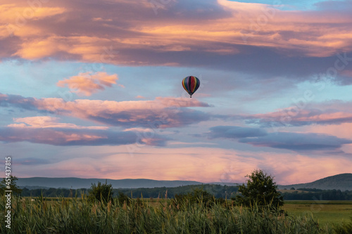 Hot air balloon over field at sunrise with amazing cloudscape sky