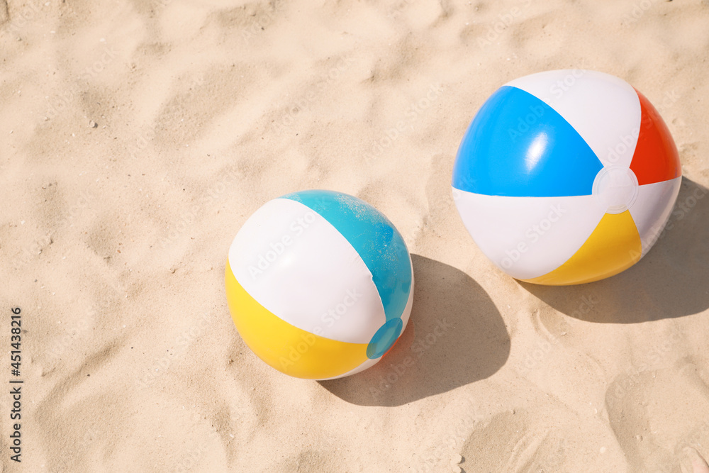 Bright beach balls on sand outdoors, above view
