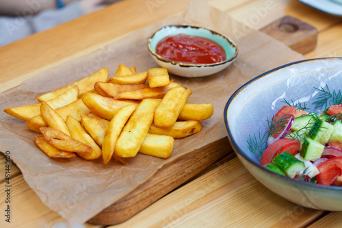 French fries with ketchup and vegetable salad in the restaurant