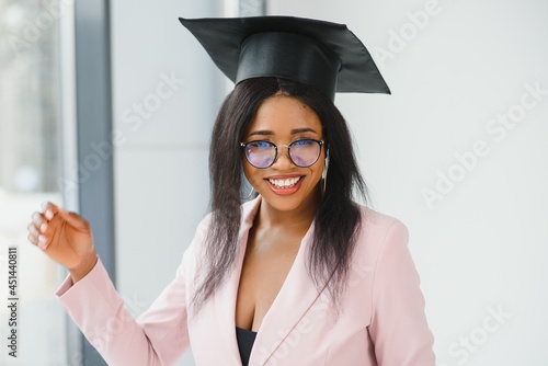Beautiful young Afro American graduate in academic dress is holding diploma