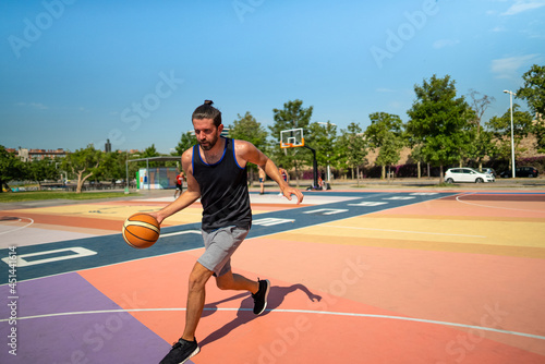 A male basketball player runs on a basketball court with a ball © Igor Kardasov