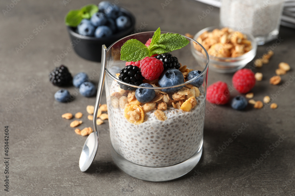 Delicious chia pudding with berries, granola and mint on grey table Delicious chia pudding with berries, granola and mint on grey table