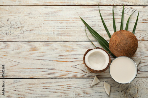 Delicious vegan milk and coconuts on white wooden table, flat lay. Space for text