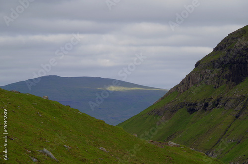 Panoramablick grüne Wiese Leynar auf Färöer Insel Streymoy mit Felsen Bergen Varga im Hintergrund - Cliffs and green Grass hills on Faroe Island Streymoy with rocks and panoramic landscape views photo