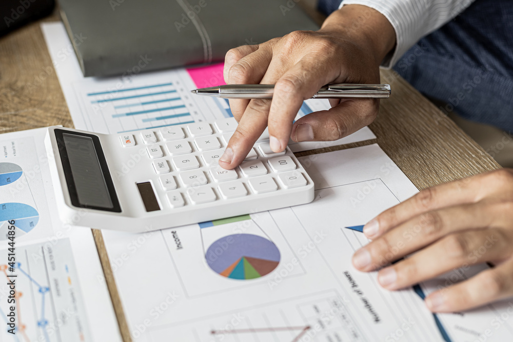 Financial scholars are pressing white calculators to calculate numbers on financial documents to verify the accuracy of company financial data line and pie chart documents. Finance concept. Financial scholars are pressing white calculators to calculate numbers on financial documents to verify the accuracy of company financial data line and pie chart documents. Finance concept.