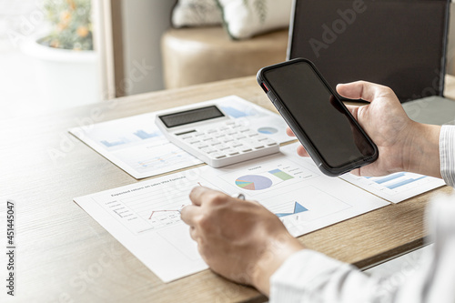 Fototapeta Naklejka Na Ścianę i Meble -  Businessman talking to a partner in a smartphone app, he is checking the accuracy of company financial data, financial status documents in line and pie charts. Finance concept.