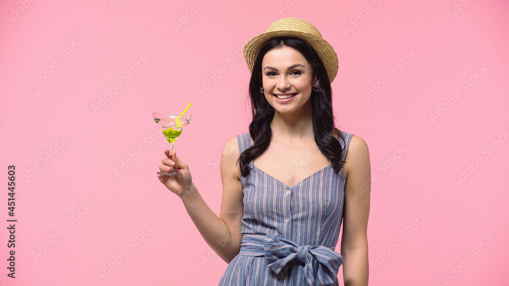 Positive woman in sun hat holding cocktail and looking at camera isolated on pink. Positive woman in sun hat holding cocktail and looking at camera isolated on pink.