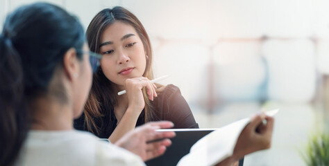 Two young business people discussing about business plan together while sitting in modern office room.