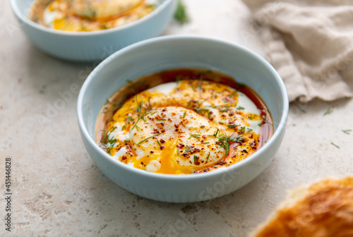 Turkish Eggs Dish Cilbır in Small Blue Bowl photo