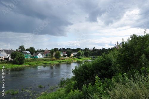 Panoramic view of the Tvertsa river. View of the river and wooden houses on the bank. Before the rain, clouds hang over the river.