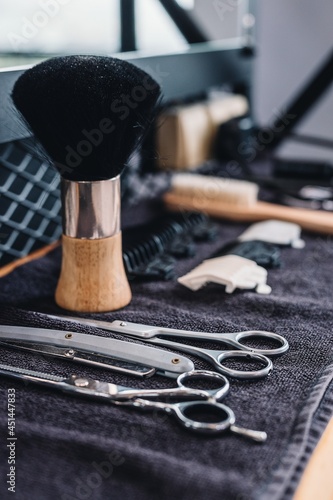 Close-up shaving brush, razor, scissors, combs on the table on a black towel. Professional barber tools and equipment. Barbershop. Professional mens shaving and haircut, hair care. Vertical shot