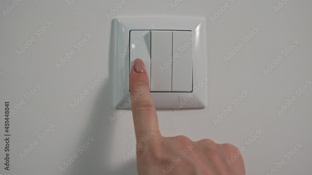 electricity, young woman turns off the light with her finger on the switch after using it, close-up electricity, young woman turns off the light with her finger on the switch after using it, close-up