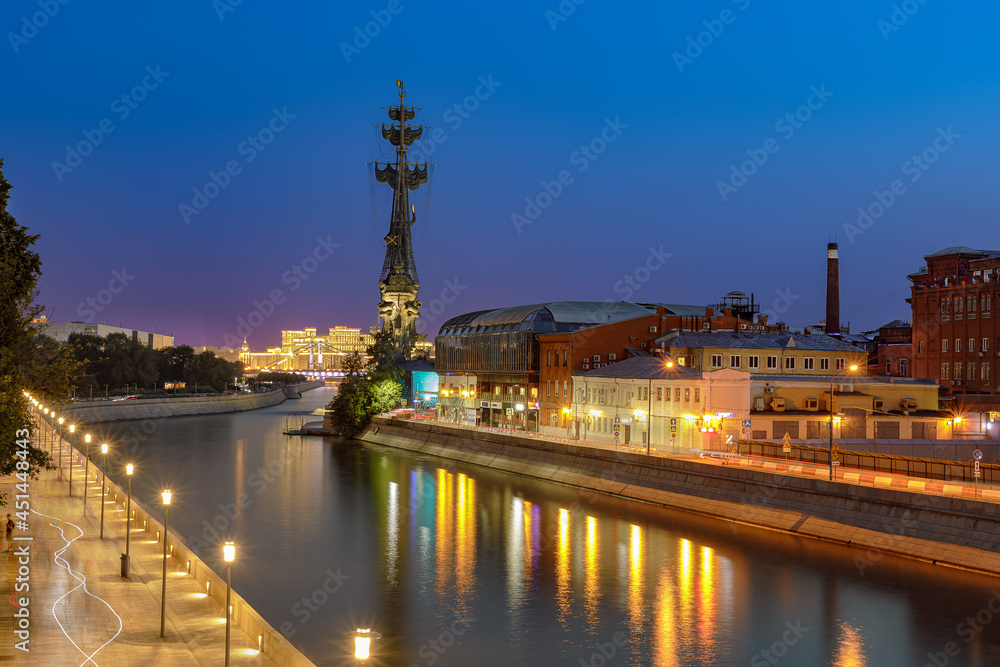 Night Moscow with evening lights on the embankment. Reflection of lanterns in the river.