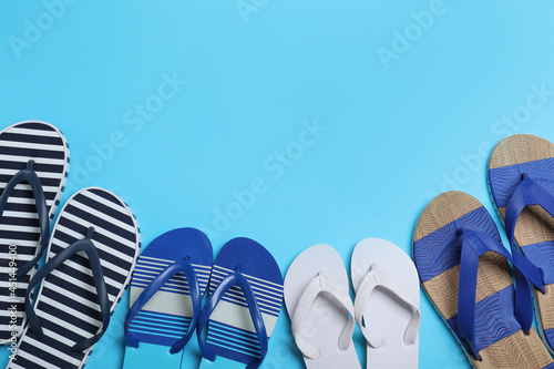 Many different stylish flip flops on light blue background, flat lay. Space for text