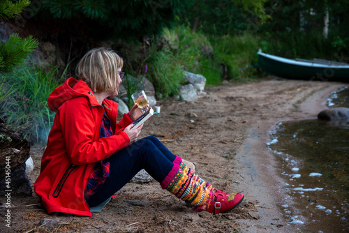 Woman sitting by the fire on the lake beach  photo