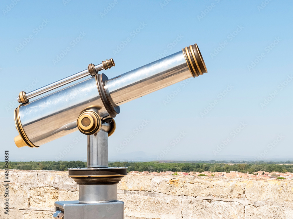 Side view of a Coin-operated binoculars looking out over a river landscape