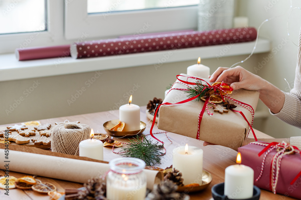 Zero waste, eco friendly christmas presents wrap concept. Young woman pack gifts in recyclable craft paper, decorate with cone, dry orange, pine branch, ribbons. Holiday atmosphere, festive mood. Zero waste, eco friendly christmas presents wrap concept. Young woman pack gifts in recyclable craft paper, decorate with cone, dry orange, pine branch, ribbons. Holiday atmosphere, festive mood.