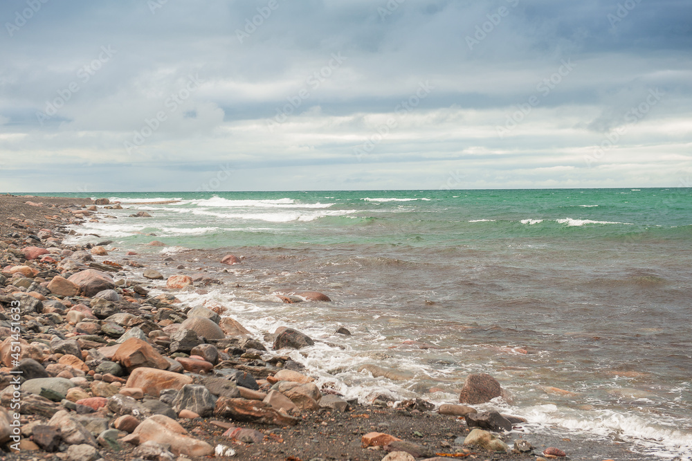 Dramatic scene with Sea waves, rocky seashore and clouds
