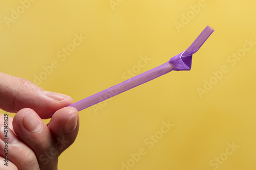 Man's hand holding a straw with a knot in it. Single-use plastic concept