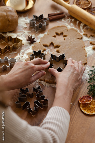 Young woman in process of baking christmas pastry, cutting cookies of gingerbread dough. Festive mood. Family culinary concept, cooking process, new year eve tradition. Holiday atmosphere of love. photo