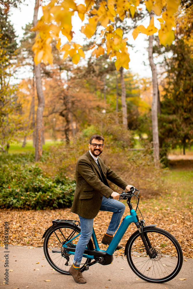 Young man with electric bicycle in the autumn park