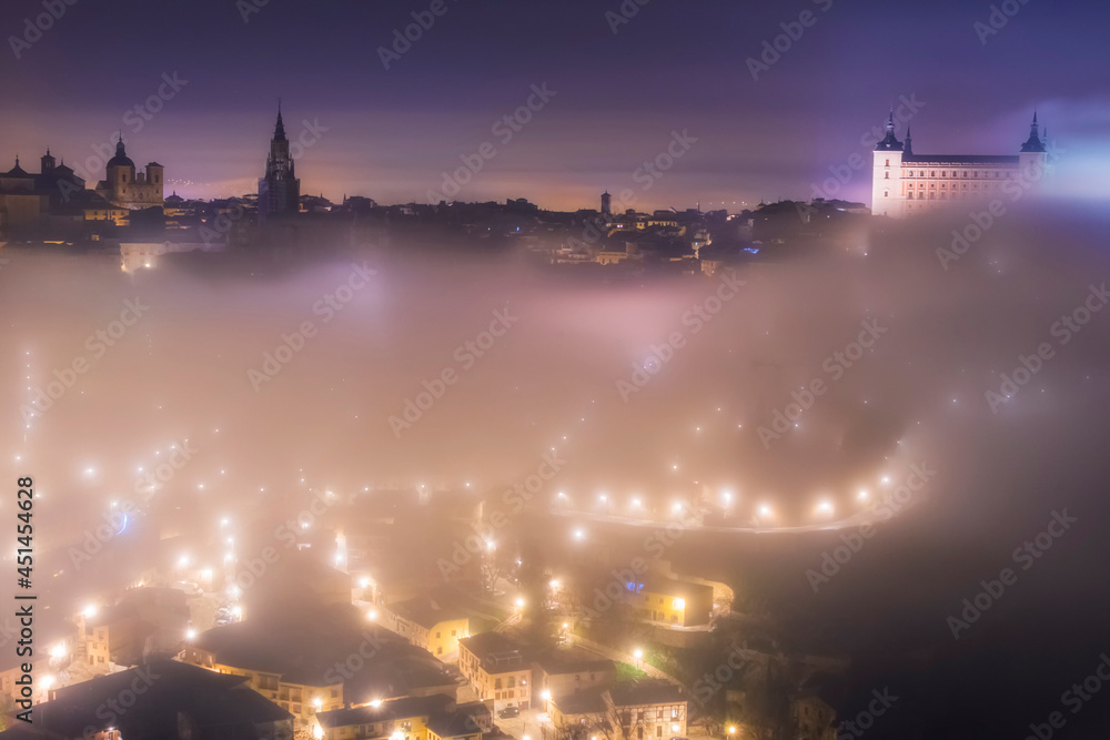 Naklejka premium Aerial night view of the skyline of the old European city on a foggy night, Toledo, Spain.