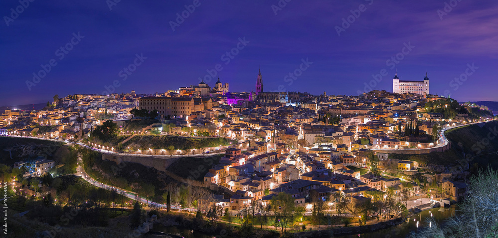 Panoramic night view with violet and purple illumination for the international women's day of the ancient European city of Toledo, Spain.
