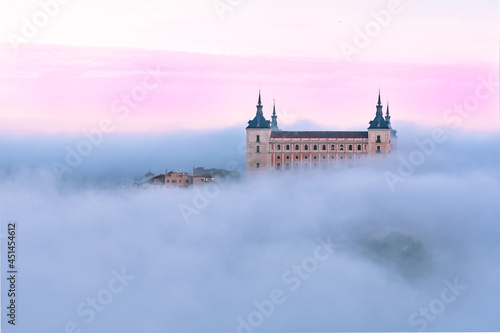 Aerial view of the ancient castle Alcazar of Toledo through the fog in colorful sunrise, Toledo, Spain.