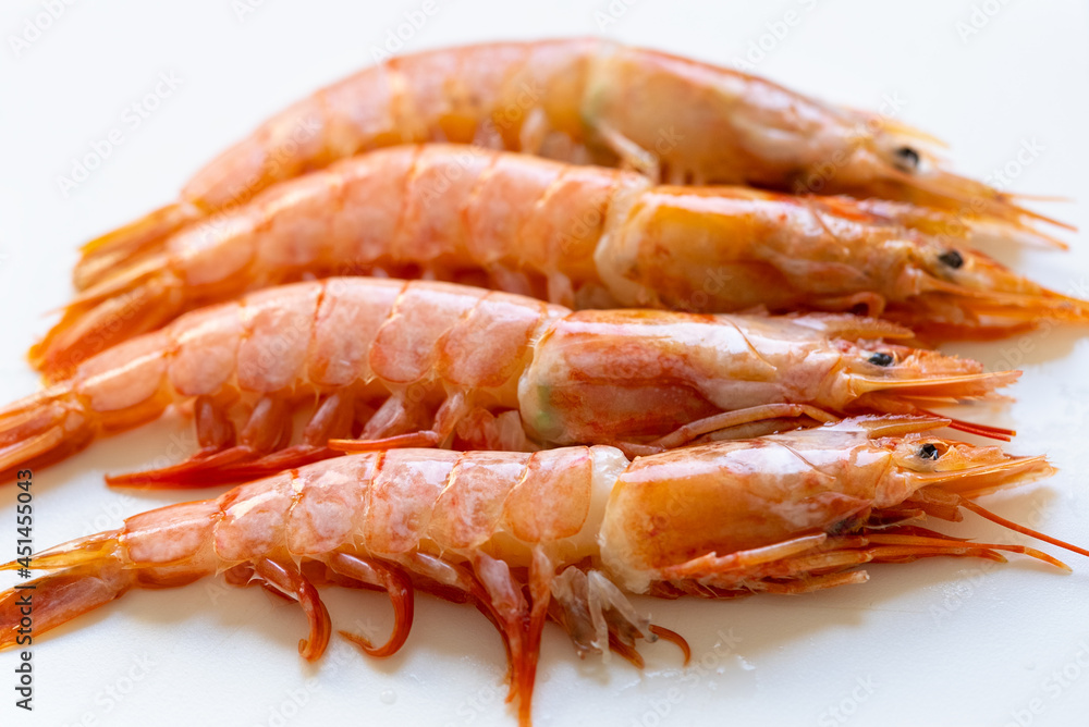 Four cold cooked pink prawns laid out in a row Four cold cooked pink prawns laid out in a row