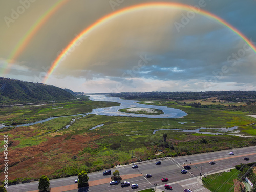 a gorgeous aerial shot of the blue lagoon waters surrounded by lush green trees and plants with blue sky, powerful clouds and a rainbow at Batiquitos Lagoon in Carlsbad California USA photo