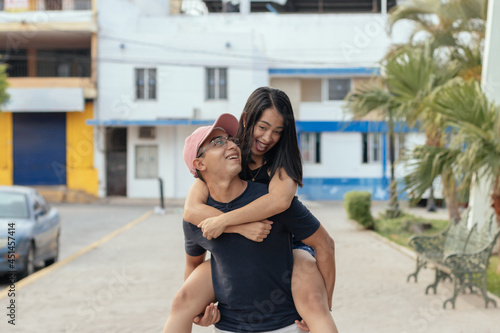 Young an carrying young woman on her back piggyback smiling