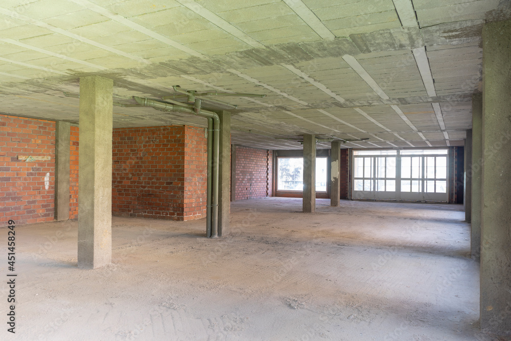 Wide-angle background image of an empty building under construction with concrete columns, construction stopped due to the economic situation.
