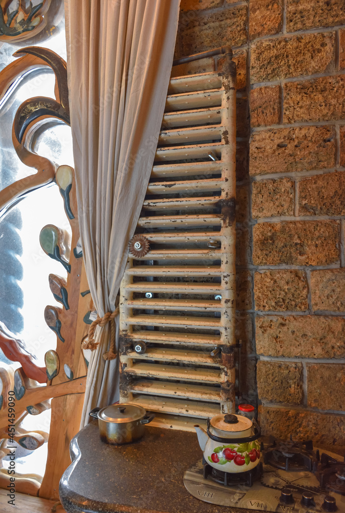 an old vertical radiator by a window with an unusual frame, next to a ...