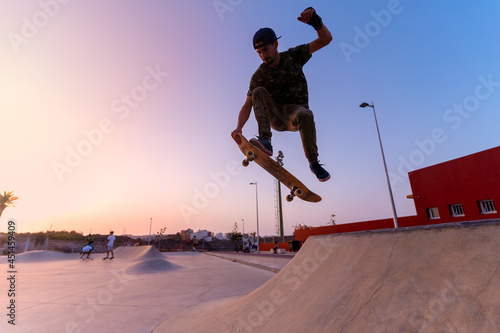 young skateboarder man jumps with his board on the ramp of a skatepark at sunset. movement 2