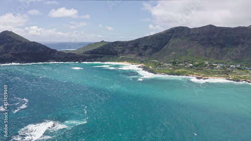 Flying over Makapuu Beach Park. Giant waves foaming and splashing in the ocean. The turquoise color of the Pacific Ocean water on tropical island. Magnificent mountains of Hawaiian island of Oahu.