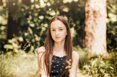 Beautiful little girl with long hair in nature in the summer. Looking into the camera