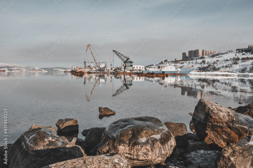 view of the docks in winter from the sea. stones in the foreground.