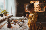 A cute sweet girl makes Christmas decorations from dried oranges, twigs and cones. Crafts for the holiday