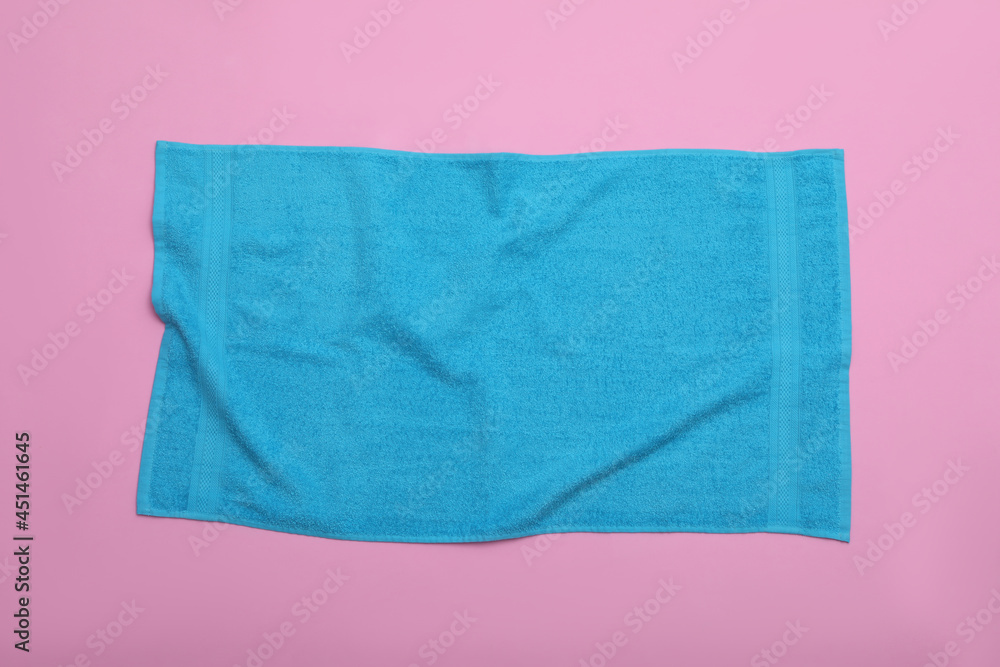 Crumpled light blue beach towel on pink background, top view
