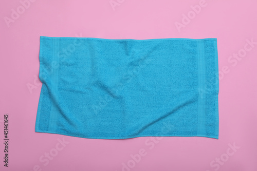 Crumpled light blue beach towel on pink background, top view