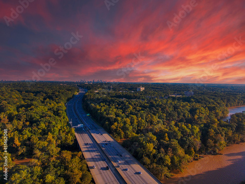 stunning aerial shot of miles of lush green trees, the freeway, the Chattahoochee river and blue sky at sunset with powerful clouds at the Chattahoochee River Recreation Area in Sandy Springs Georgia