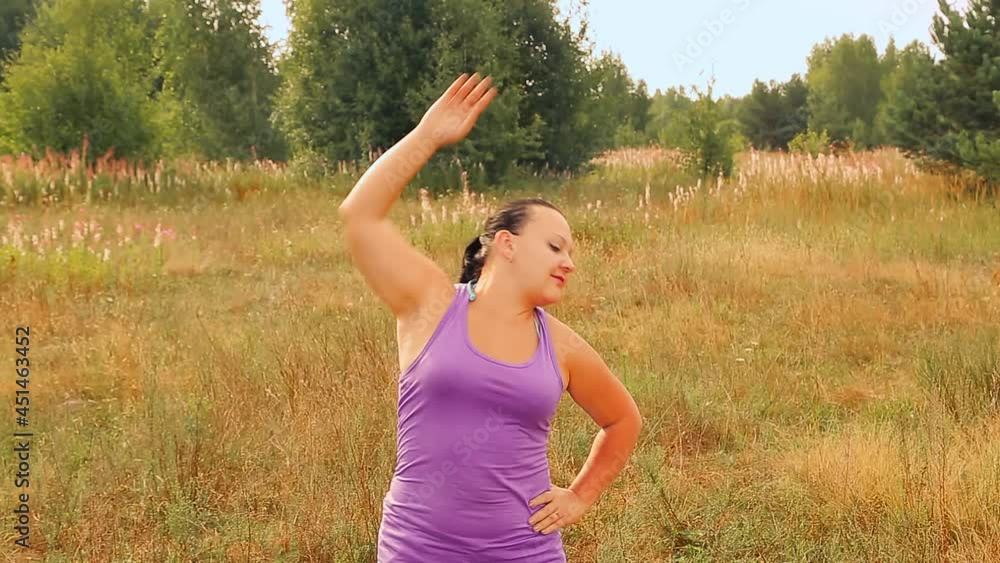 A young woman in the morning on the meadow does gymnastics A young woman in the morning on the meadow does gymnastics