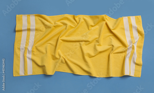 Crumpled yellow beach towel on blue background, top view